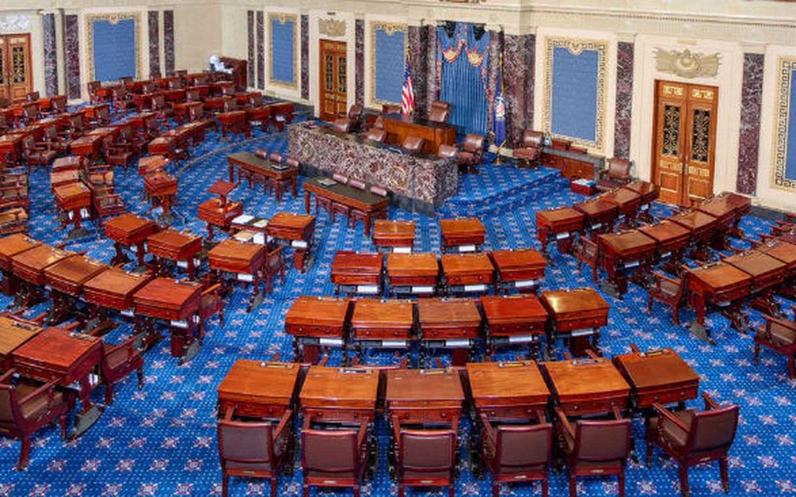 Empty rows of wooden desks and chairs fill the US Senate chamber